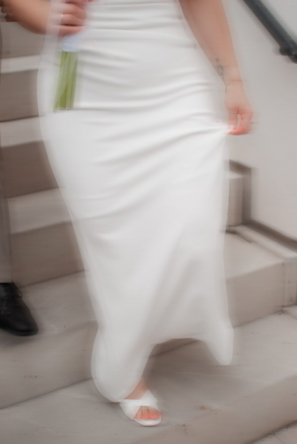 Braut im weißen Kleid geht die Treppe hinunter, das Kleid in Bewegung